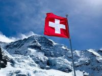 Taxes Switzerland Swiss flag in front of the world famous „Mönch“ 