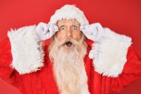 Santa Claus Old senior man with grey hair and long beard wearing santa claus costume holding glasses afraid and shocked with surprise and amazed expression, fear and excited face.  amazement,surprise,astonishment