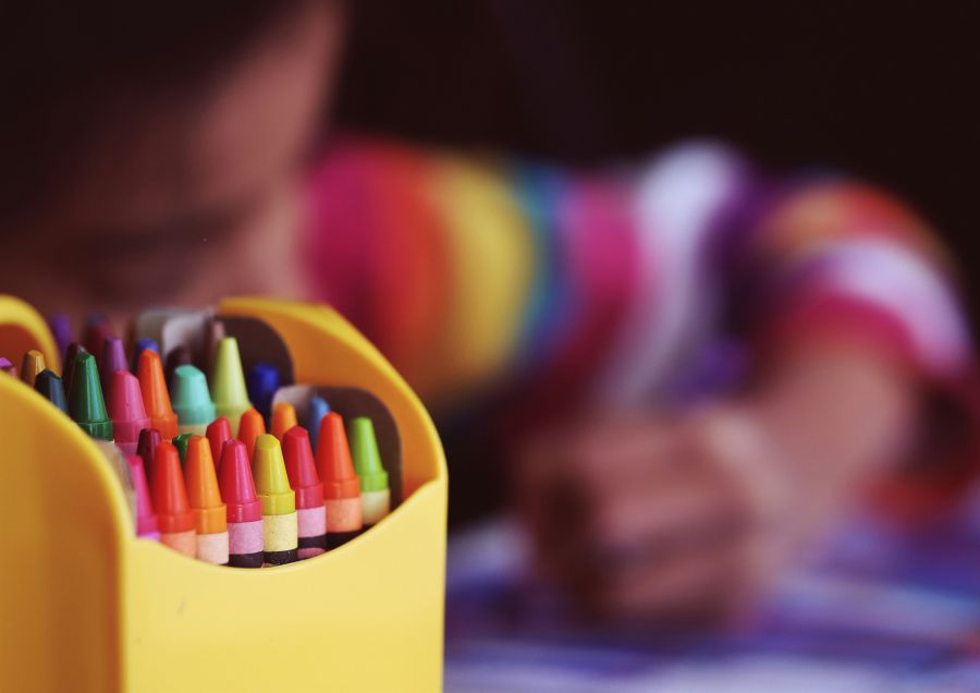 Childcare Crayons beside child coloring 