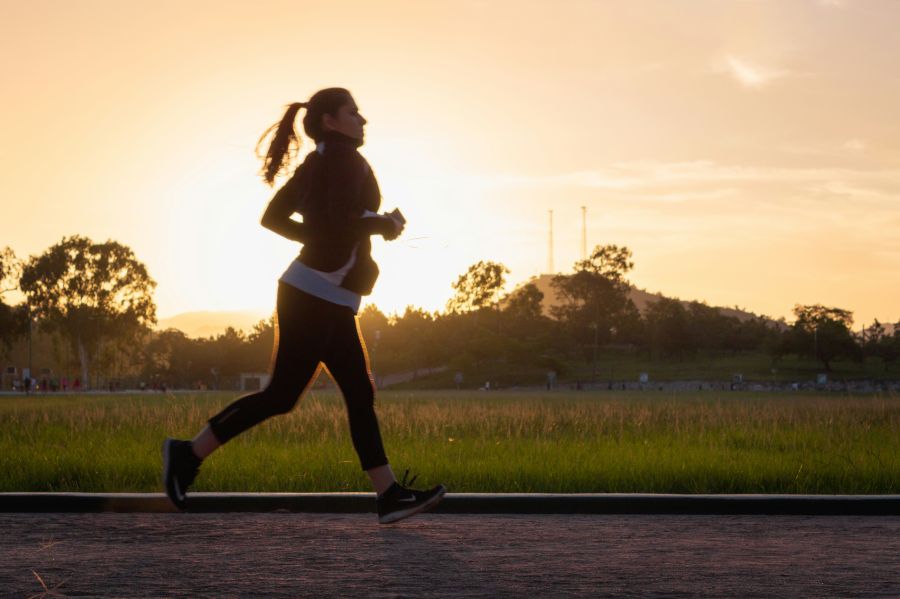 Jogging Woman running on track at sunset.