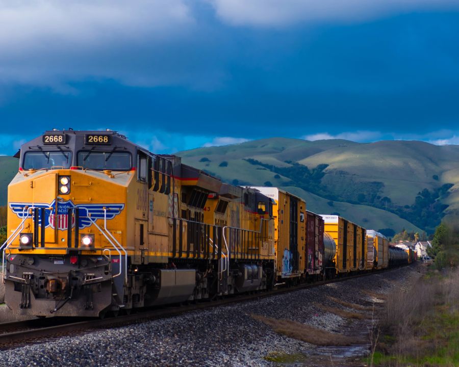 Railway Investment I loved the analagous colors formed by the yellow train, green hills, and blue sky. I love the country feel this photo has with the rolling green hills in the background and the freight train coming right through. 