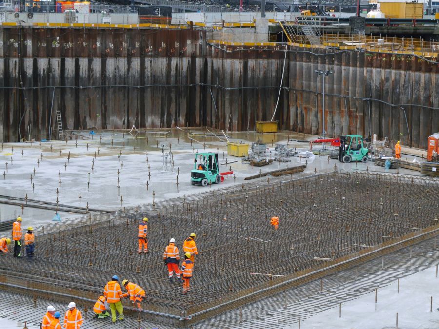 Metro Construction Construction site with workers on the concrete bottom, fixing the steel wire construction ground of the excavation site;. Then the concrete can be poured. This becomes an underground parking place for circa 8000 bicycles in front of Central Station, Amsterdam. The rusty pile sheeting wall is necessary to keep the construction pite safe and dry, because of the wet soggy bottom of Amsterdam city. Free urban photo of Amsterdam constructions - Dutch city photography of work by Fons Heijnsbroek, Neth 