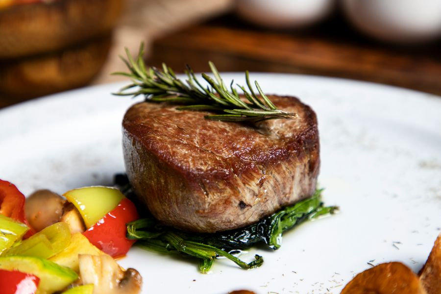 Meat Dish A succulent steak plated with roasted peppers, mushrooms, and greens, ready to serve for meat lovers and fine dining enthusiasts 