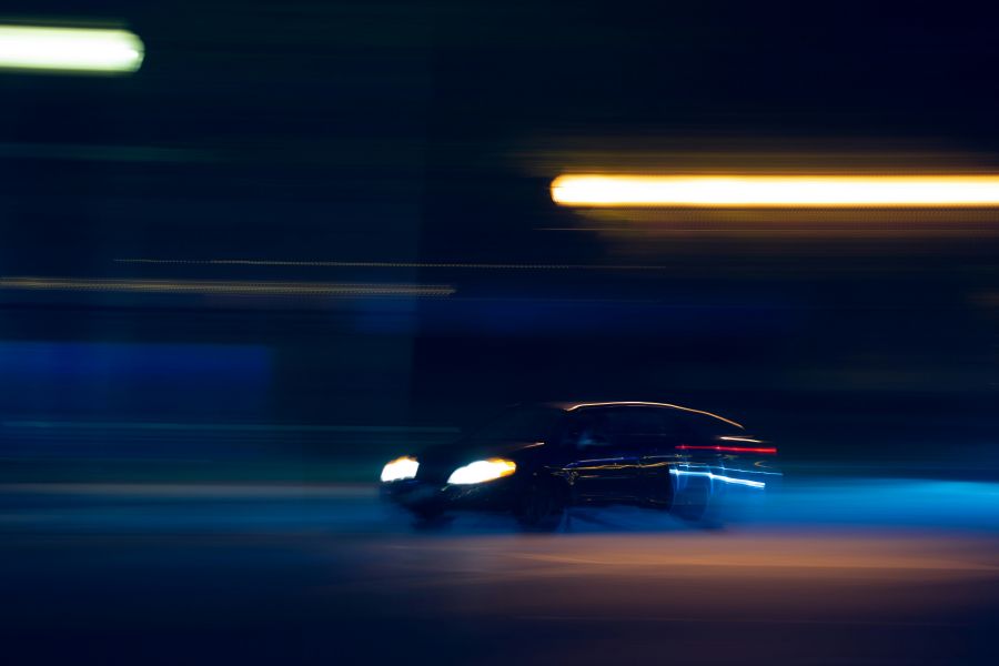 speeding A car speeds through a blurred city street late at night.  