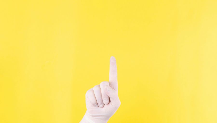 Doctor trial The close plan. Doctor's hand in a white medical glove on a yellow background shows up. The medicine. Place for an inscription. Advertising. Like. Medical gloves. clinical,surgeon,uniform